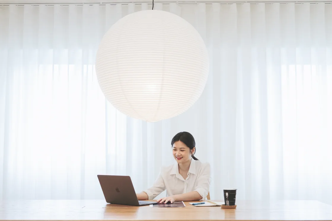 Lauren 在明亮的工作桌前，微笑使用筆記型電腦
